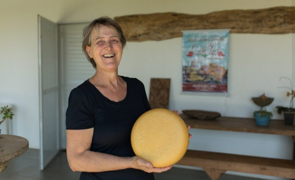 Produtora da Queijaria Cornélia segurando um gouda inteiro